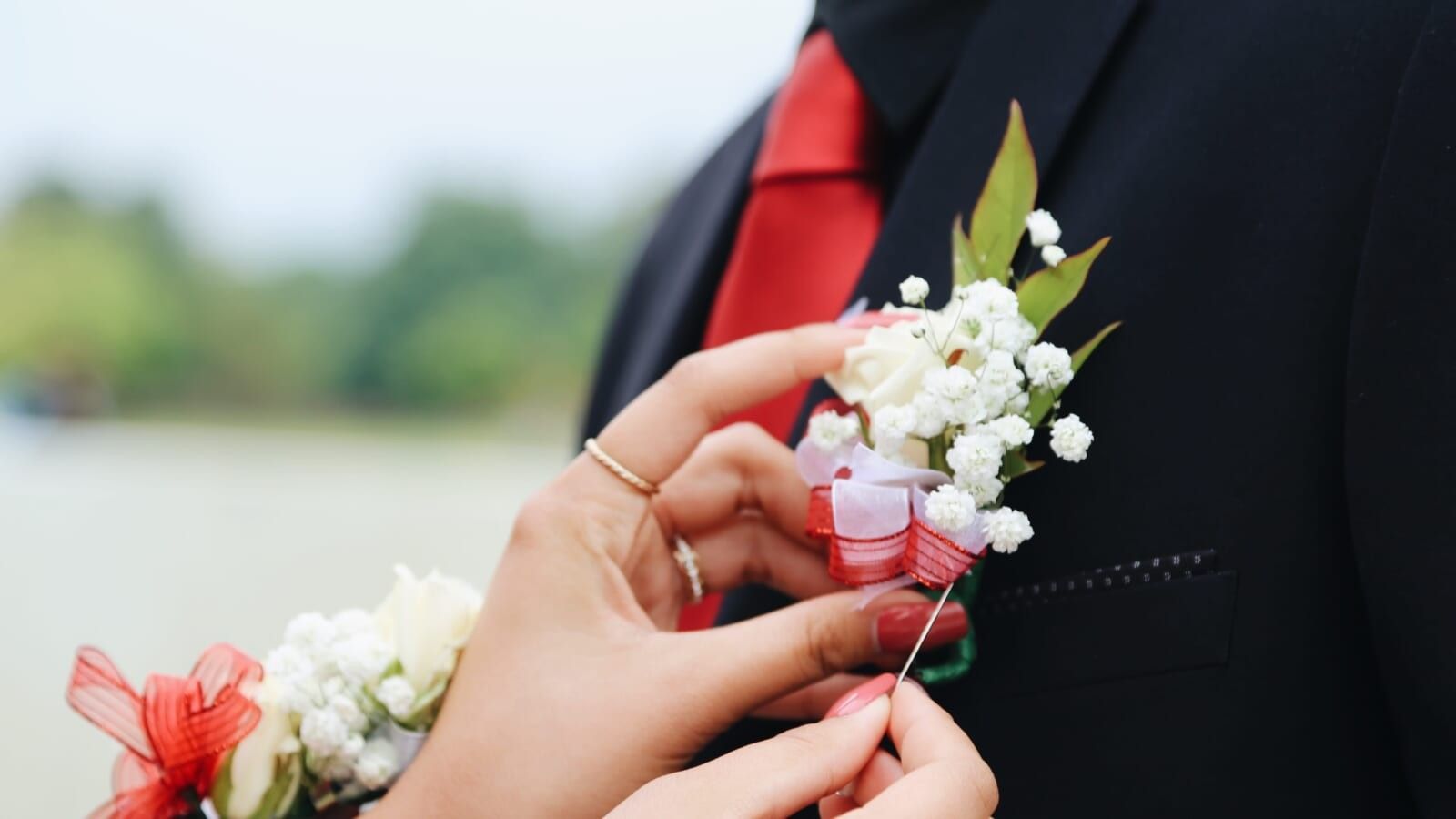person pinning a corsage on a man