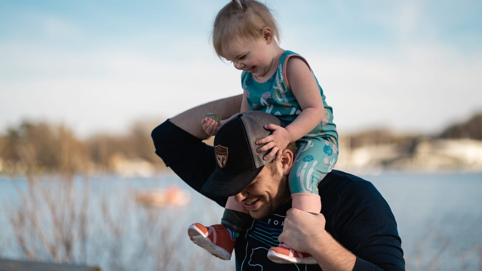 man in black shirt carrying a toddler on his shoulders