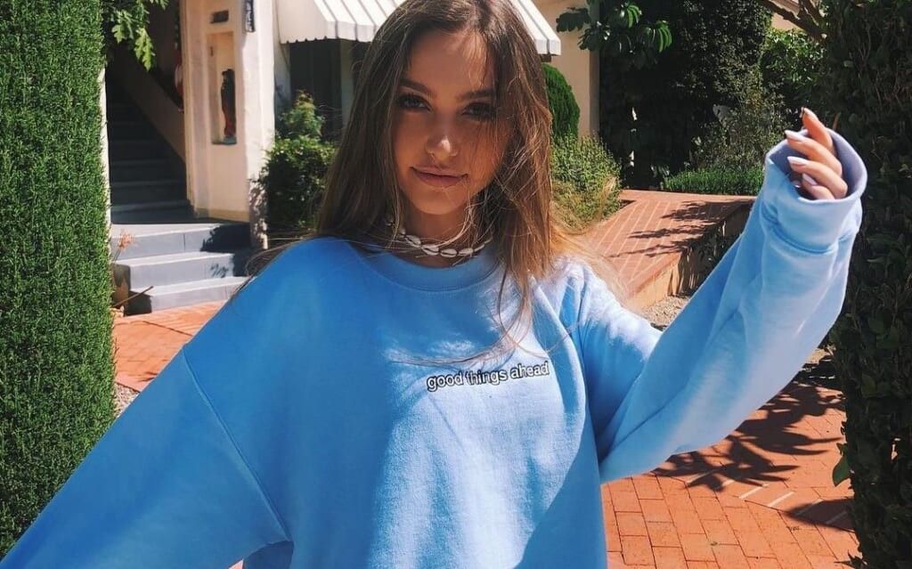 young woman poses in sweater outside