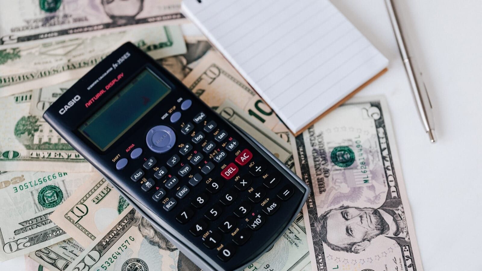 calculator and notepad lying on money