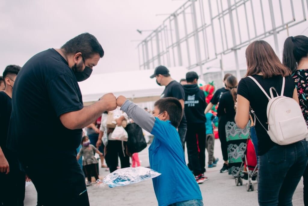 man in a black shirt fist bumping a little boy wearing a blue shirt 