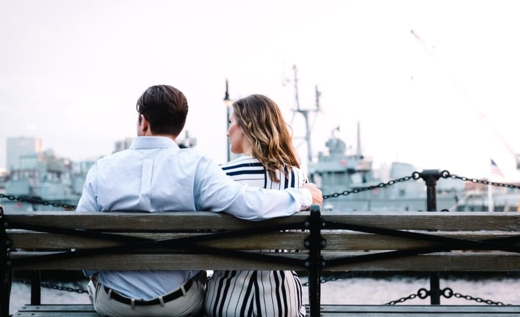 young couple sit on bench together