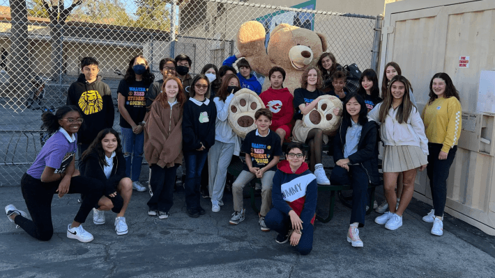children standing with a huge teddy bear soft toy