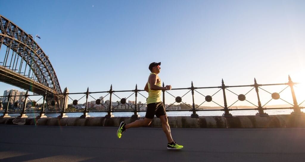 man runs on concrete beside the water