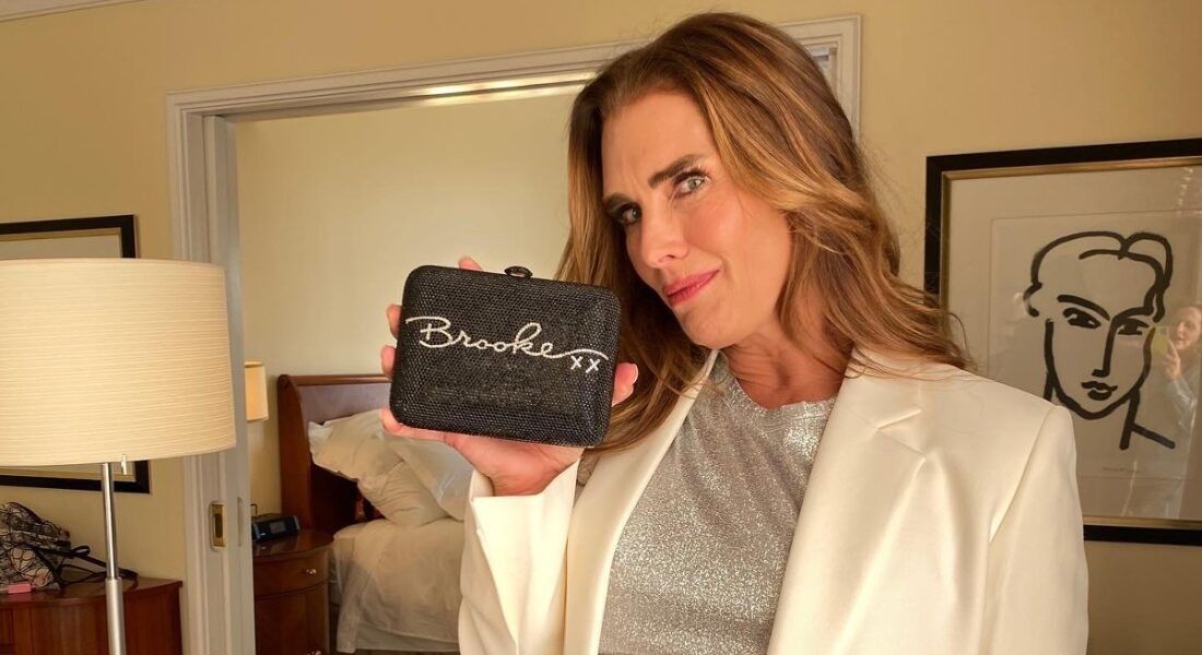 Brooke Shields in white suit holding a Brooke sign. 