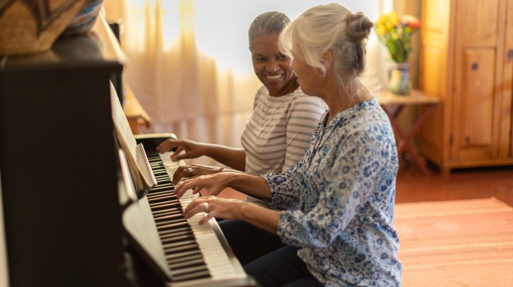 two women play piano together
