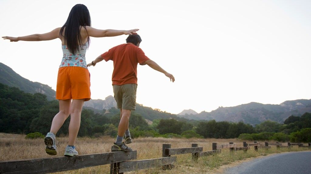 Man and woman walking across wooden fence