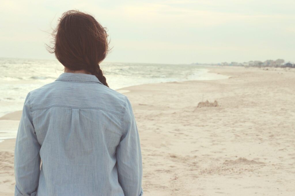 dark-haired-woman-facing-sandy-beach