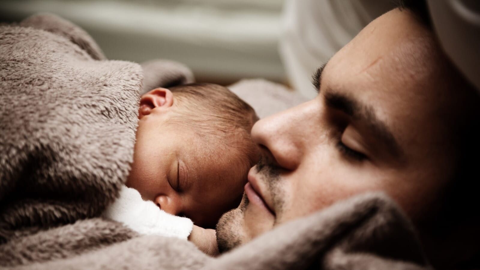 man sleeping with baby on his chest