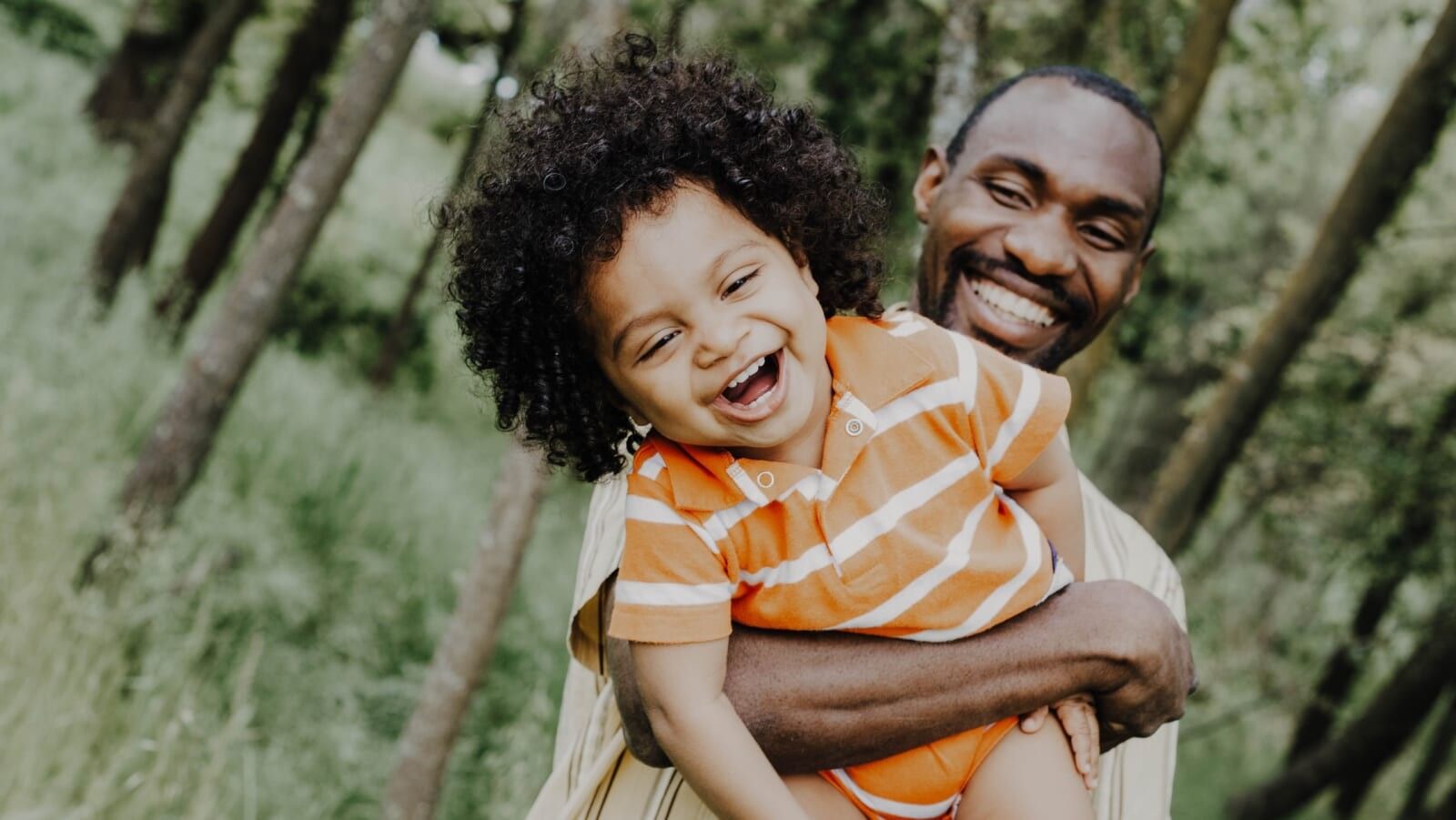 smiling man lifting a little child