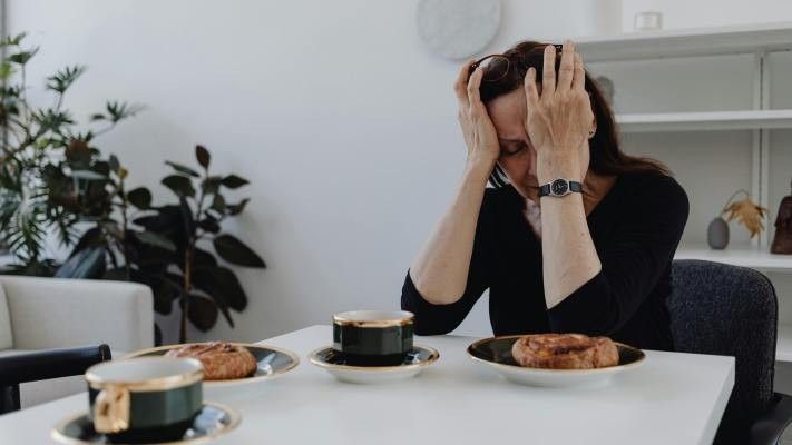 grieving woman sitting at a dining table