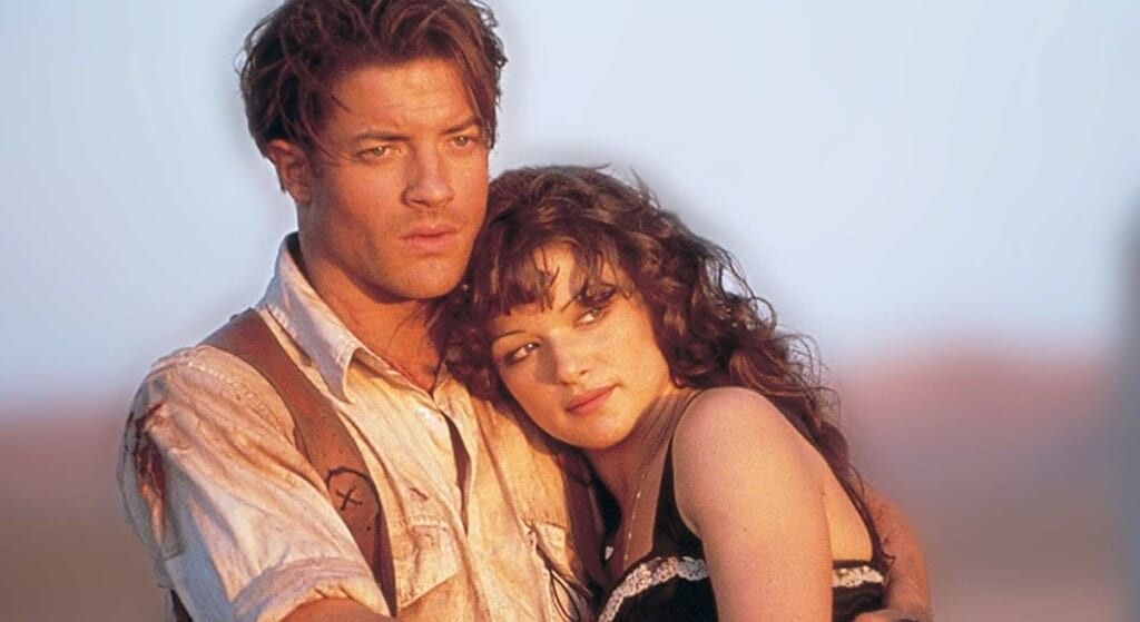 Brendan Fraser covered in dust holding Rachel Weisz.