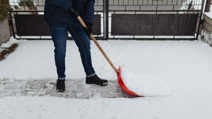 person in a winter jacket shoveling snow