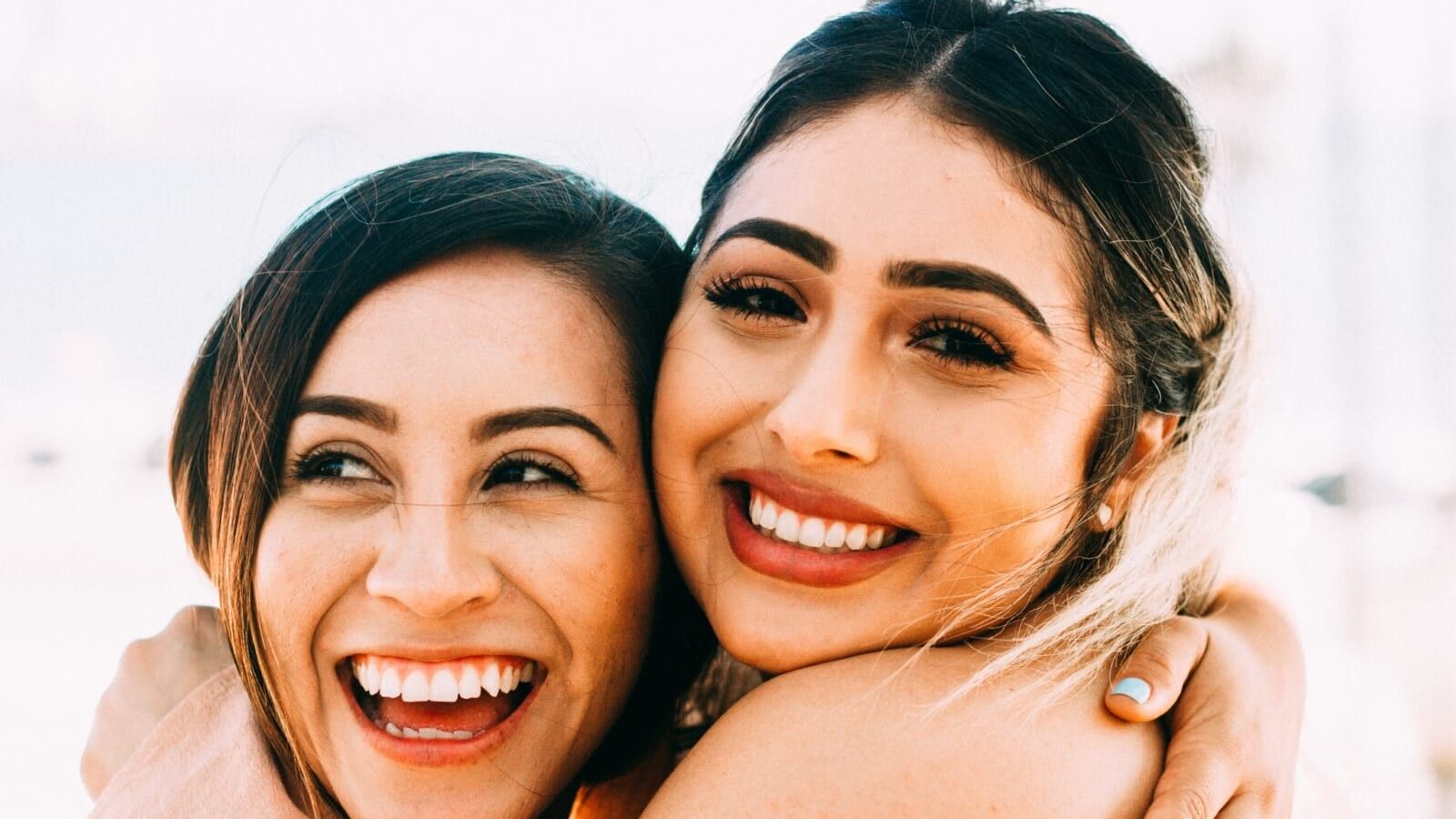 two women laughing and hugging each other