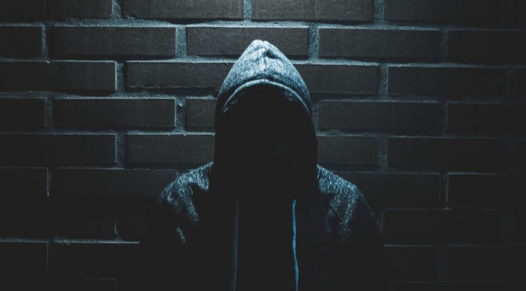 Man in Hoodie against a dark brick wall