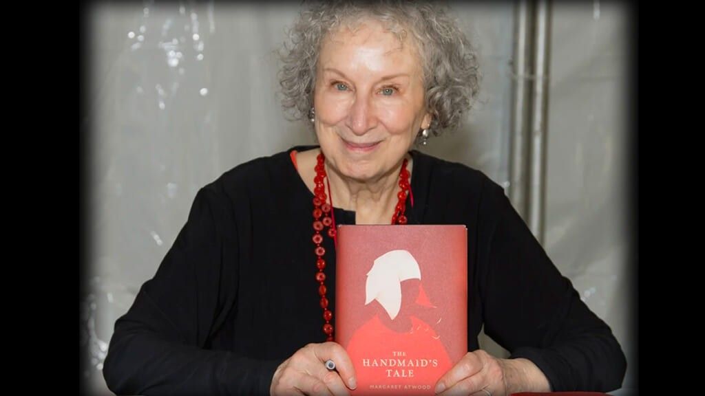 Margaret Atwood holding a copy of a Handmaid