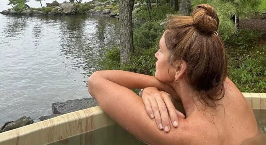 Cindy Crawford topless in hot tub looking at scenery.