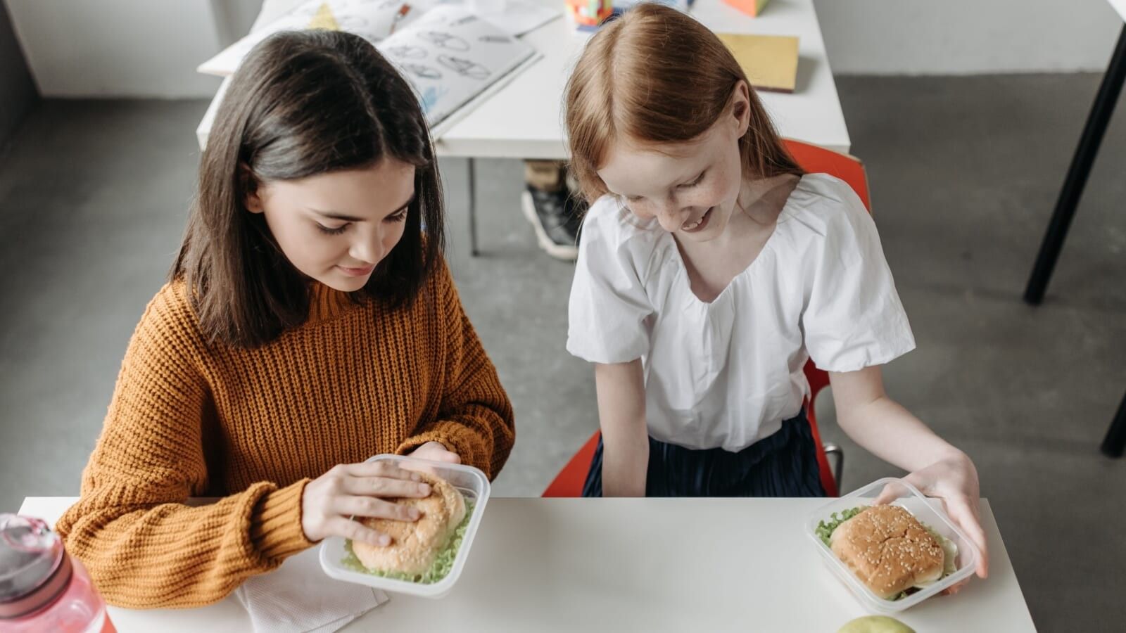 two girls sitting at a table with food