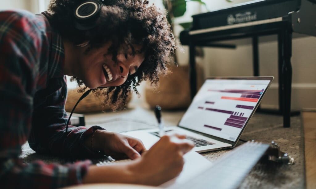 young woman sits on the floor writing lyrics to her song