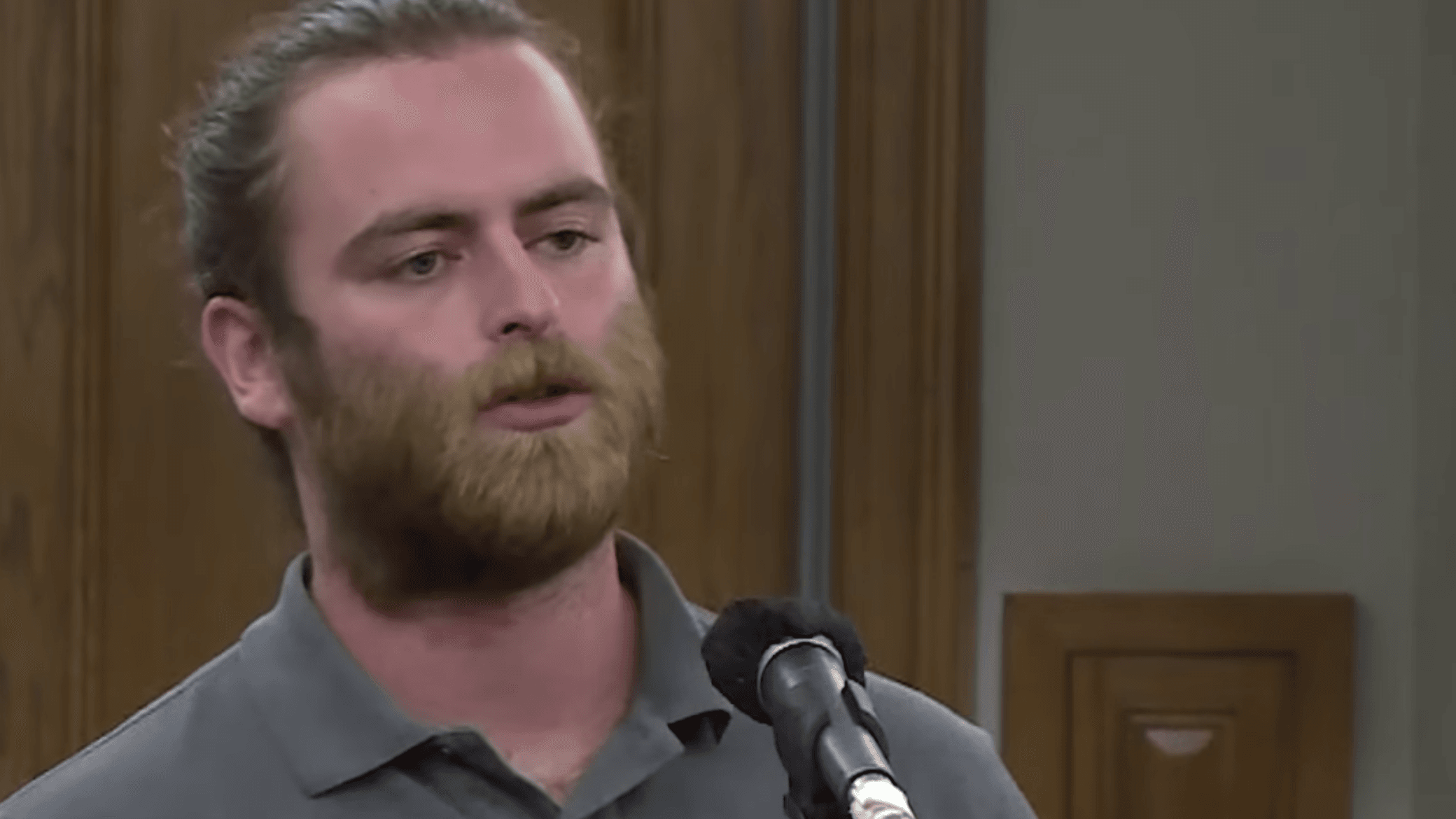 man with a beard standing in front of a mic