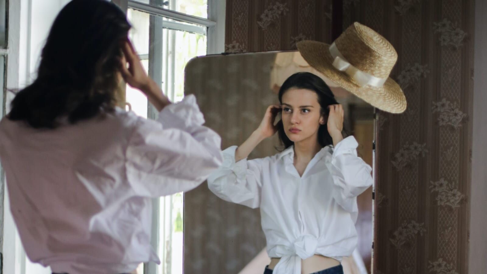 girl in white shirt standing in front of a mirror
