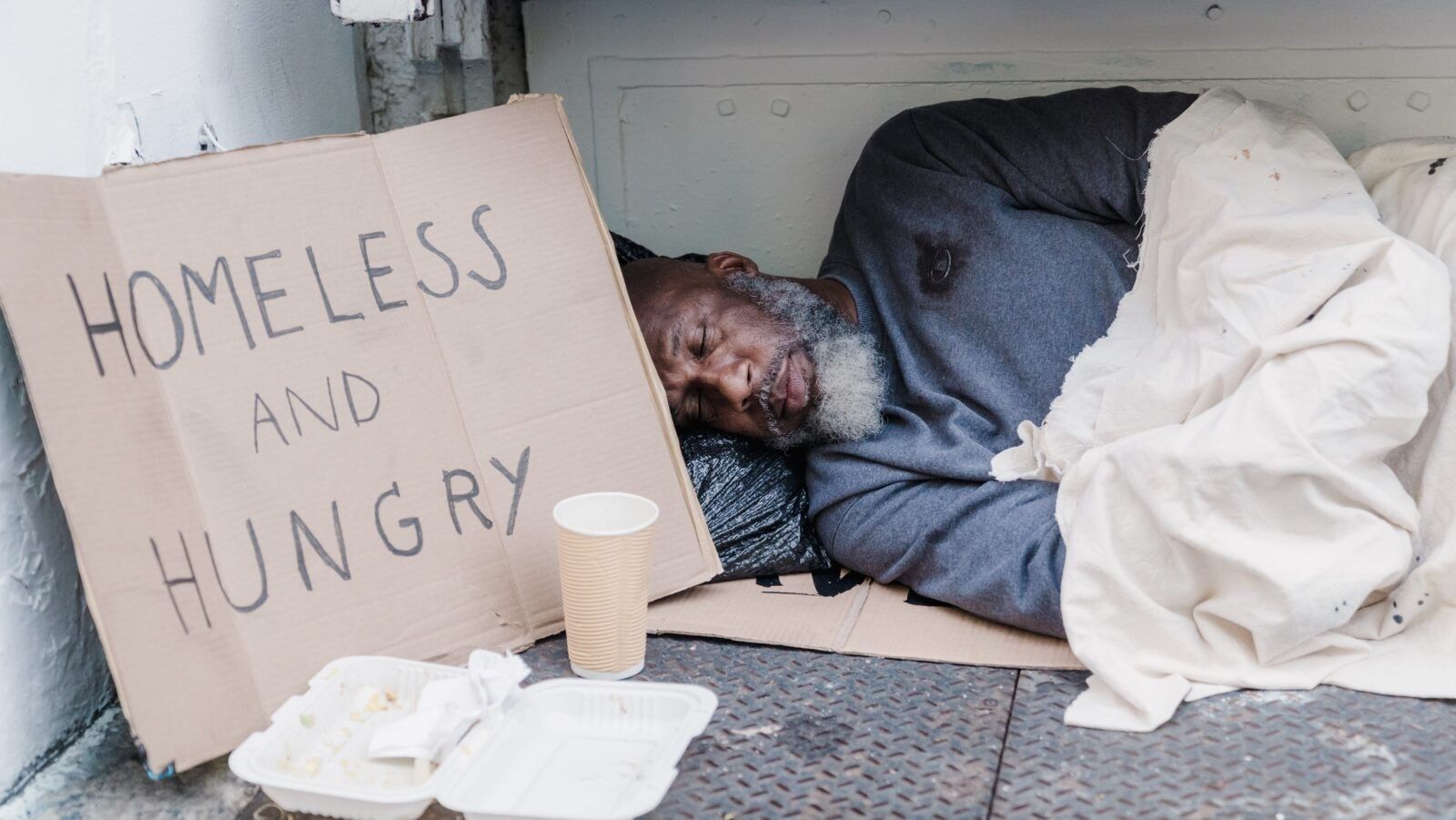 man sleeping on the ground next to a sign reading
