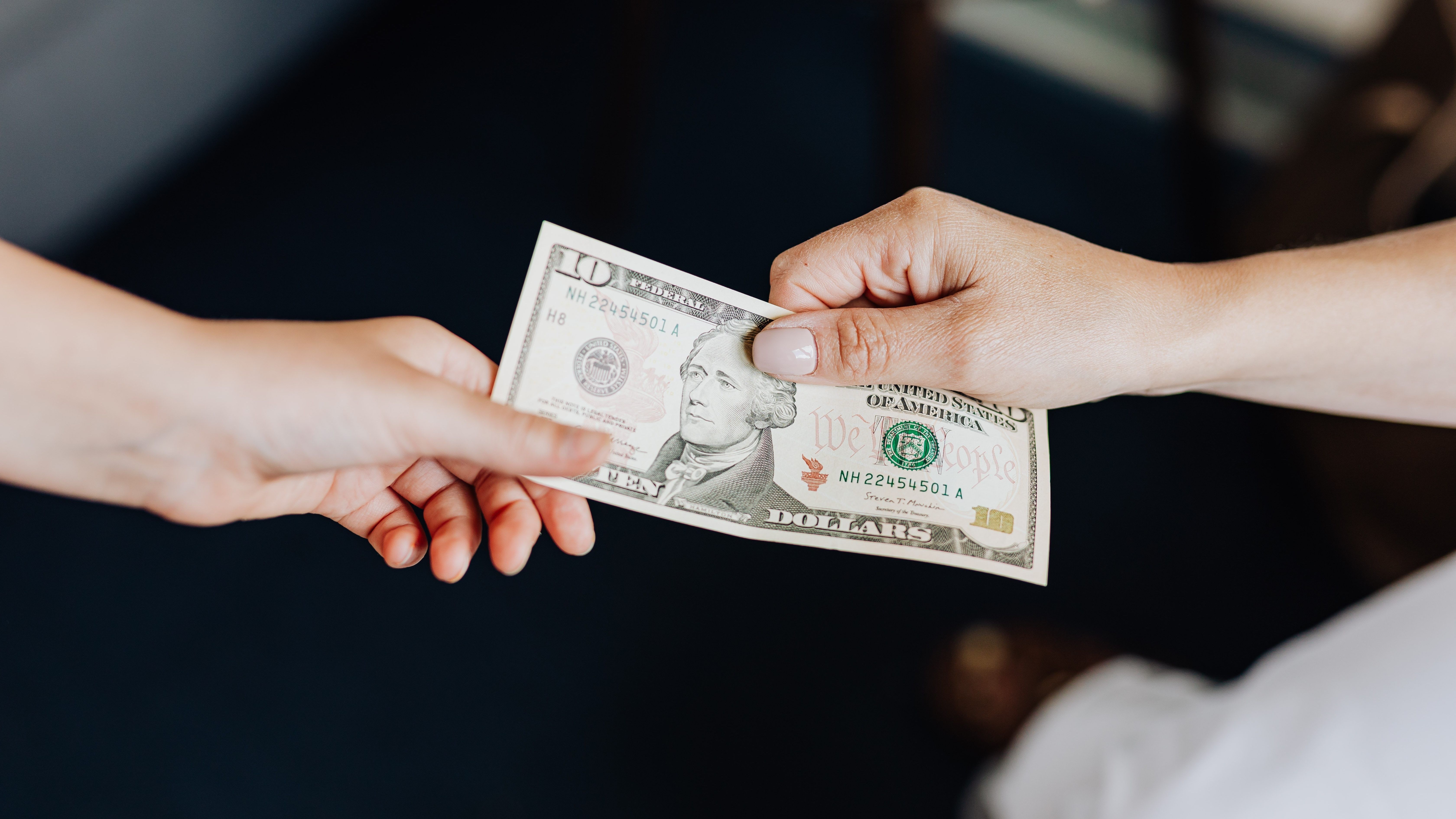 person handing a dollar bill to another person