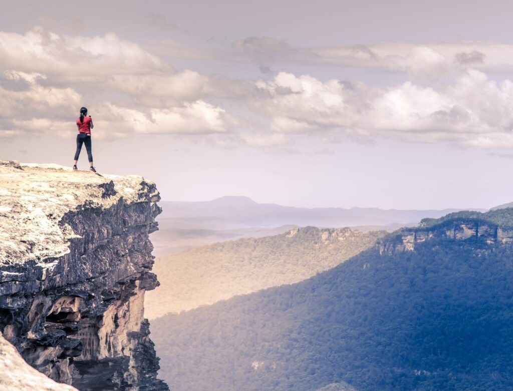 woman-standing-top-tall-mountain-feeling-free