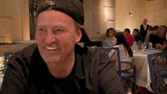 man smiling and wearing a baseball cap