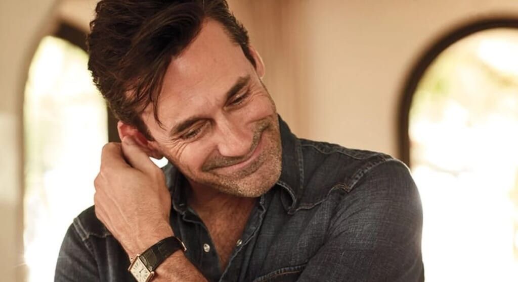 Jon Hamm in grey sweater laughing.
