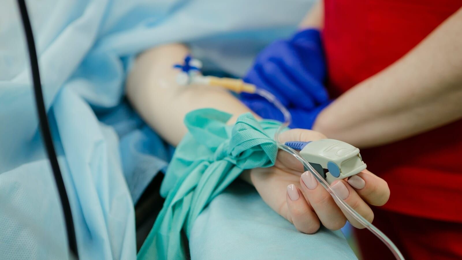 person lying in hospital bed and another person standing next to them