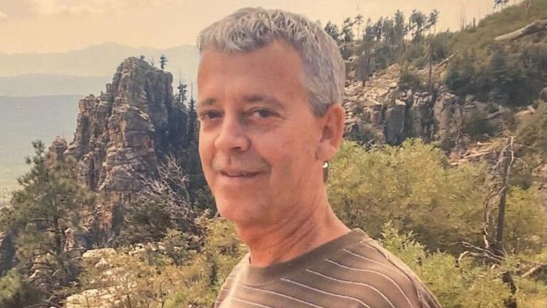 a man standing in front of greenery