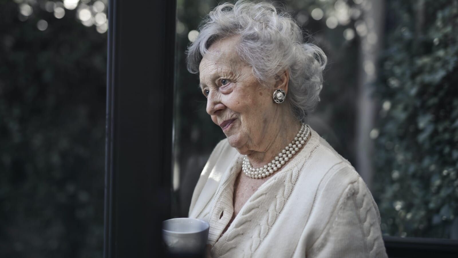 elderly woman wearing pearl necklace and white outfit
