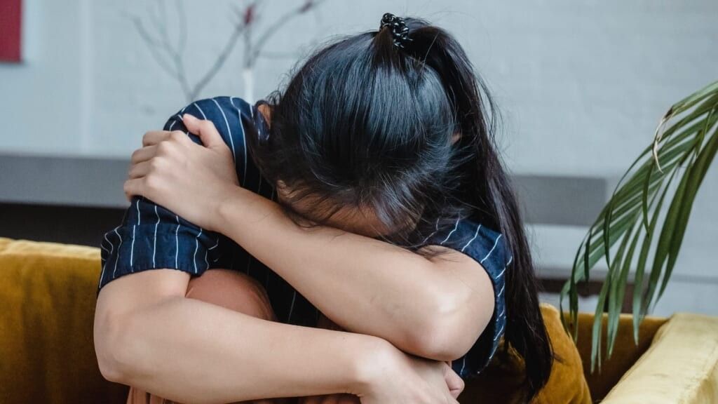 woman in a ponytail crying on the couch