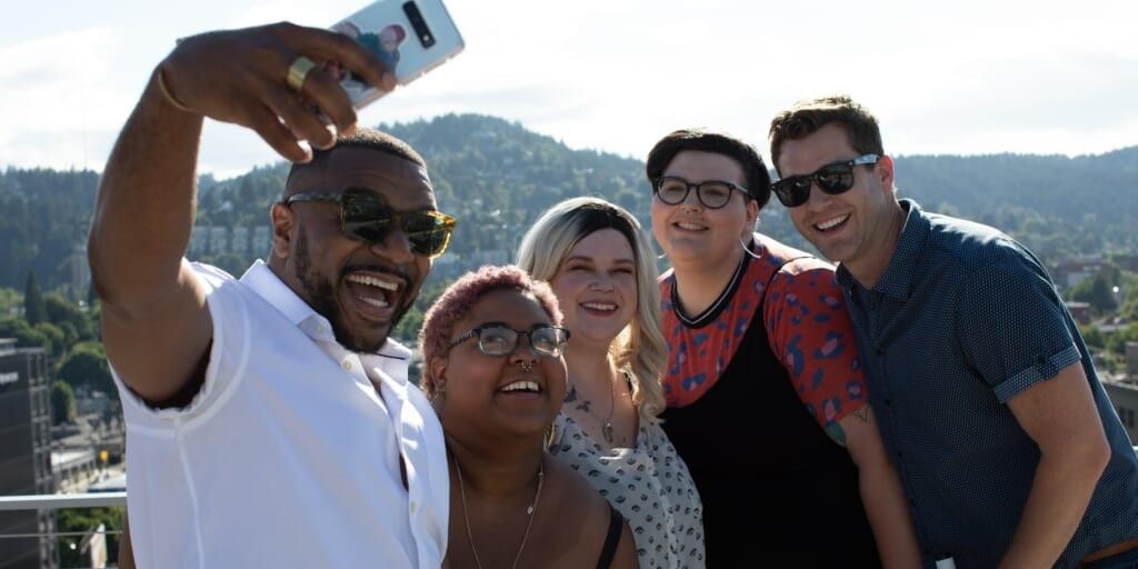 Group of friends taking selfie on rooftop overlooking city by Allgo on Unsplash
