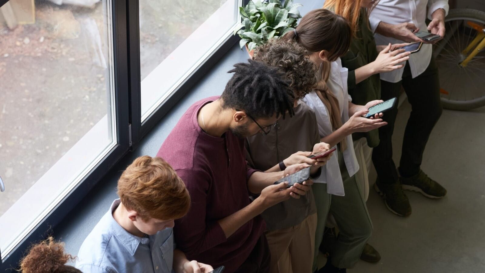people standing in a line and checking their phones