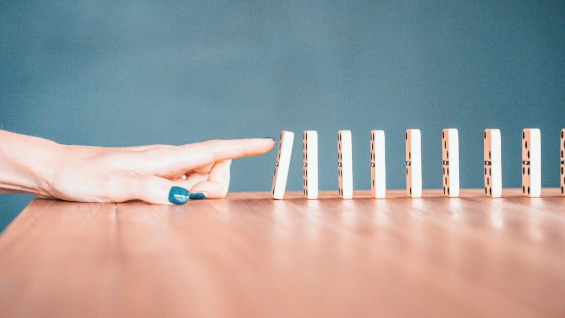 person touching dominos standing in a row