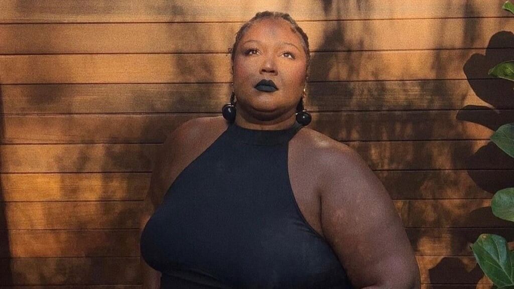 Lizzo posing in a black dress