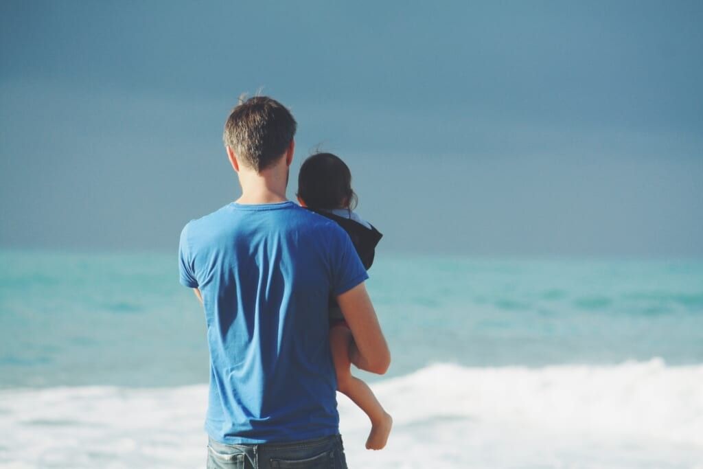 dad and baby on beach looking out on water