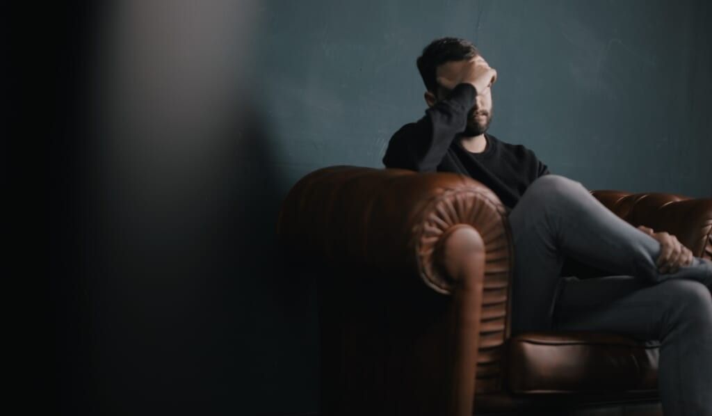man with face on hand in therapy