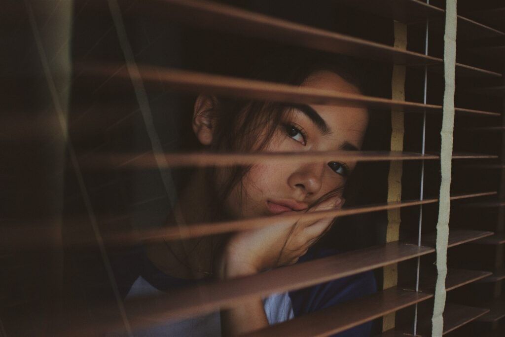 Woman-looking-through-shutters